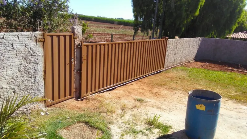 Portão metálico marrom de correr com porta social